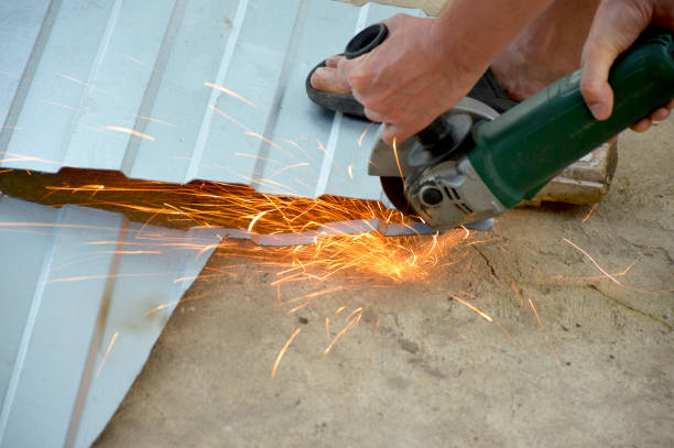 A person using a power shear to cut a metal roofing sheet